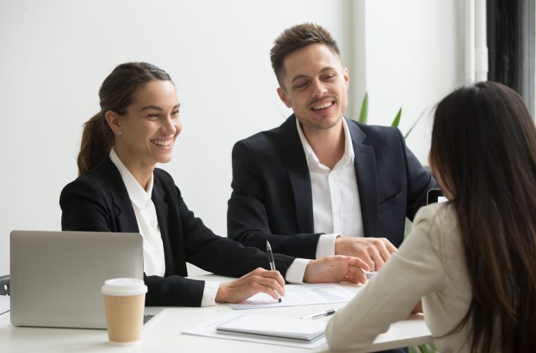 Friendly business team members chatting laughing together during office break, happy coworkers talking having good relations and pleasant conversation at work, smiling hr interviewing job applicant
